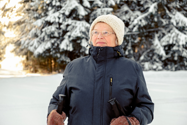 Senior woman outdoors in a snowy forrest with walking sticks