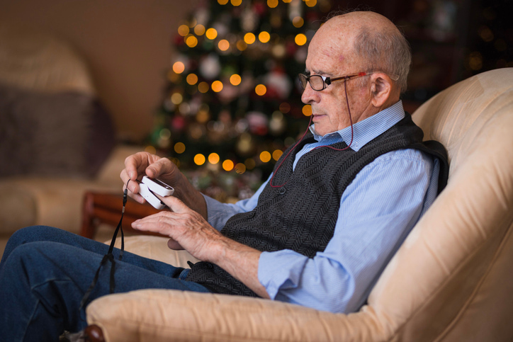 Senior taking blood oxygen reading on his finger. Festive bacjground.