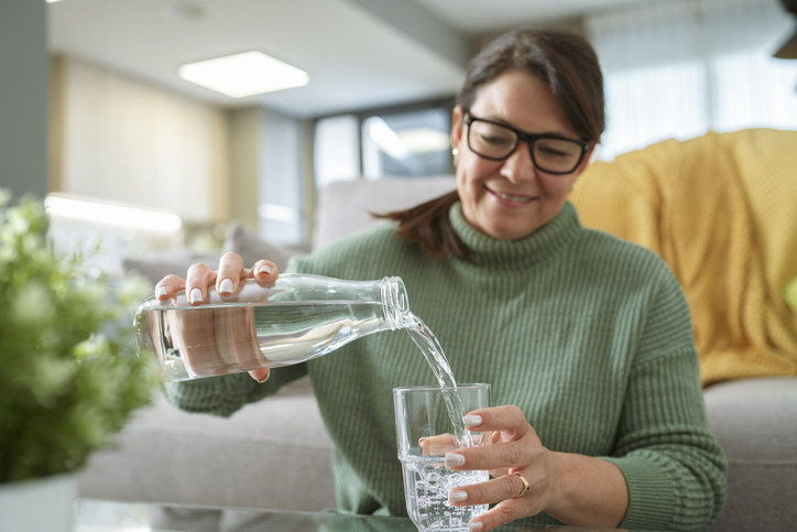 Close up of a woman pouring water from bottle into a glass