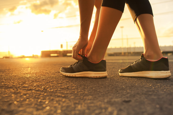 Runner tying shoes at sunset