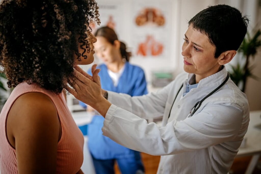 Female doctor checking womans neck